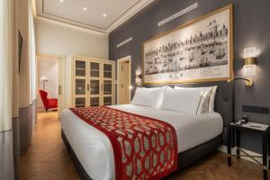 a bedroom with a large bed with a red blanket at Áurea Casa Palacio Sagasta by Eurostars Hotel Company in Cádiz