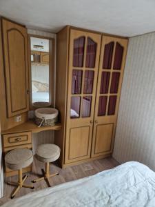 a bedroom with a cabinet and two stools next to a bed at Ruime 6 persoons Orlando Super in De Pol