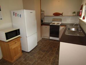 a kitchen with a white refrigerator and a sink at Shack 93 - James Well in Perara