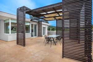 a pergola on a patio with a table and chairs at Agreste Luxury Apartments in Paliouri