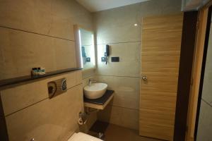 a bathroom with a sink and a toilet and a mirror at Goodland Elegance in Trivandrum