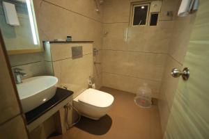 La salle de bains est pourvue de toilettes blanches et d'un lavabo. dans l'établissement Goodland Elegance, à Trivandrum