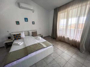 a bedroom with a large bed and a window at Vila Ithea in 2 Mai