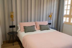 1 dormitorio con 1 cama rosa y 2 almohadas en Suites Chinitas, en Málaga