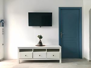 Habitación con TV y vestidor blanco con puerta azul. en Rising Sun House Santorini en Firostefani