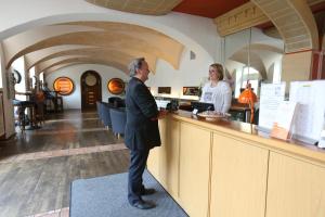 特里尔Kolping Hostel Trier im Warsberger Hof的站在柜台旁的一男一女
