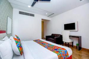 ein Schlafzimmer mit einem Bett, einem Sofa und einem TV in der Unterkunft FabHotel Golden Temple Paradise in Amritsar