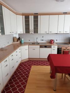 uma cozinha com armários brancos e um tapete vermelho em Blackforest FeWo em Freudenstadt