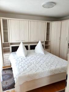 a bedroom with a large white bed with builtin cabinets at Blackforest FeWo in Freudenstadt