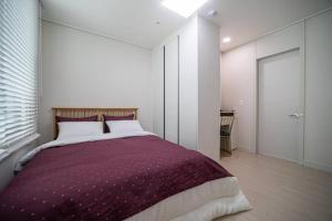 a bedroom with a large bed with purple blanket at Comma in Daejeon