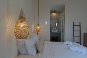 Maeva Suites Santorini في بيرغوس: غرفة نوم بسرير ابيض عليها منشفتين