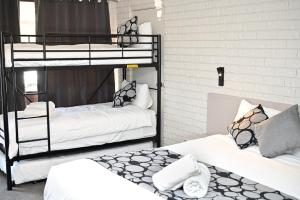a room with two bunk beds with white sheets at Woomargama Motel in Woomargama