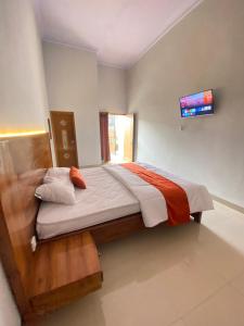 Umyas Hotel Syariah في Nganjuk: سرير كبير في غرفة مع تلفزيون على الحائط