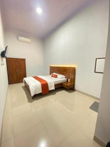 a bedroom with a bed in a room with white walls at Umyas Hotel Syariah in Nganjuk