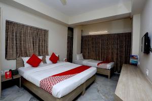 um quarto com 2 camas e almofadas vermelhas em Collection O Tulsi Palace em Nagarbazar