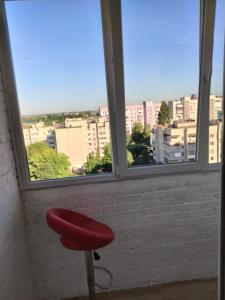 einem roten Stuhl vor einem Fenster in der Unterkunft Однокімнатна квартира Olympya біля парку Героїв Майдану in Luzk