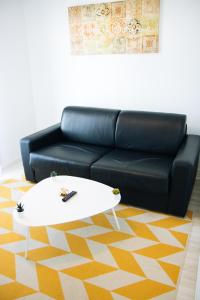 ein schwarzes Sofa und ein weißer Tisch im Wohnzimmer in der Unterkunft Twenty Business Flats Nîmes Trigone in Nîmes