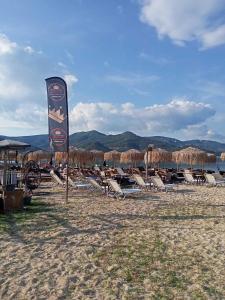 a group of lounge chairs and a sign on a beach at Maria's maisonette Nea Iraklitsa in Iraklitsa