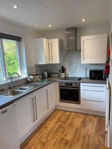 a kitchen with white cabinets and a wooden floor at Seawinds in Ventnor