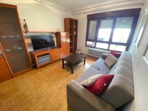 Amplio apartamento con todas las comodidades en Oviedo في أوفِييذو: غرفة معيشة مع أريكة وتلفزيون