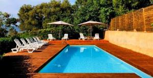 una piscina con lettini e ombrelloni di Joli 2 chambres sur Lumio, vue à couper le souffle. a Lumio