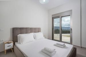 een witte slaapkamer met een groot bed met handdoeken erop bij Jarko Luxury Houses in Argoulidhés