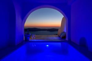 a blue room with a swimming pool with a view at Abyssanto Suites and Spa in Imerovigli