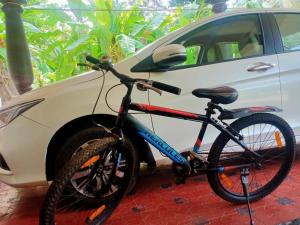 a bike parked next to a white car at Sinai Homestay in Alleppey