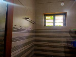 y baño con ducha y ventana. en Sinai Homestay en Alleppey