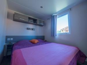 a bedroom with a purple bed and a window at Camping Les Grillons in Embrun