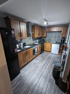 a kitchen with wooden cabinets and a black refrigerator at Belfast Waterworks Townhouse in Belfast