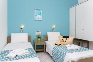 2 camas en una habitación con una pared azul en Sunshine Garden Apts, en Malia