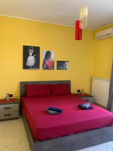 a bedroom with a red bed with a yellow wall at Casa vacanza Ilaria in Torre Lapillo
