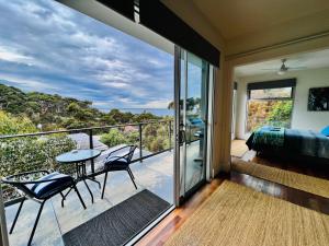 a bedroom with a balcony with a table and chairs at Sunrise on Falie Seaview Eco Accommodation in American River