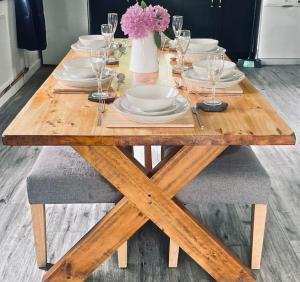a wooden table with plates and wine glasses on it at Corner Patch Retreat in Hoel-galed