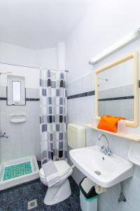 een badkamer met een wastafel, een toilet en een spiegel bij Sunshine Garden Apts in Malia