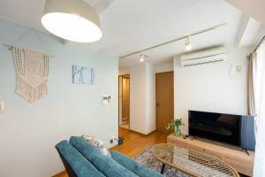 a living room with a blue couch and a tv at Elle's Shirokane Guest house 301 in Tokyo