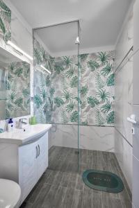 een badkamer met een douche, een wastafel en een glazen deur bij 3BD Beach Paradise with a Stunning View + Parking in Nesebar