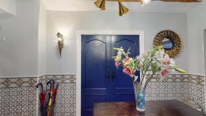 a vase of flowers on a table in front of a blue door at Casa Lucia in Caniles