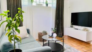 a living room with a blue couch and a tv at Sundsvall By M - Basement Studio in Sundsvall