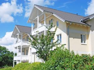 a large white building with balconies and a tree at Wohnpark Stadt Hamburg - Apt. 46 in Binz