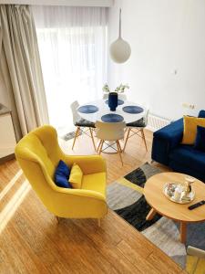 Sala de estar con silla amarilla y mesa en Apartamenty Lux Pogorzelica, dwupoziomowy, dwie łazienki, dwa tarasy, pies gratis!, en Pogorzelica