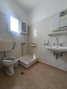 a bathroom with a toilet and a sink and a tub at Galini Rooms Sikinos Travel in Sikinos
