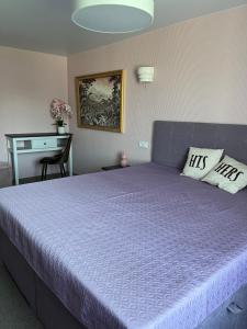 sypialnia z dużym łóżkiem z fioletową pościelą i biurkiem w obiekcie Targaleseta guest house w mieście Windawa