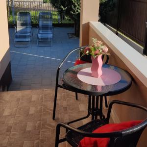 a table with a vase of flowers on a patio at Sweet Summer Apartman Zsory in Mezőkövesd