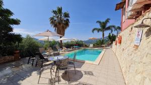 un patio con mesa y sillas junto a una piscina en Alcantara Natura Country House en Graniti