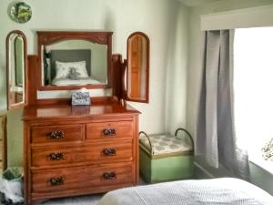 a bedroom with a dresser with a mirror and a bed at Beech Cottage in Hepple