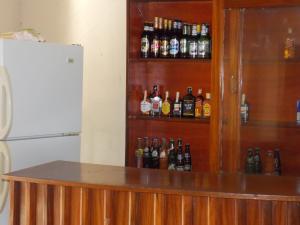 una mensola con bottiglie di alcol accanto a un frigorifero di Botanical Skyway Inn Entebbe a Entebbe