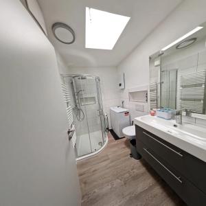 La salle de bains blanche est pourvue d'une douche et d'un lavabo. dans l'établissement Ferienwohnung Wiehl Sonnenterrasse, à Wiehl