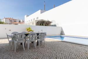 uma mesa e cadeiras ao lado de uma piscina em Villa Buganvilia by ALGARVEMANTA em Vila Nova de Cacela